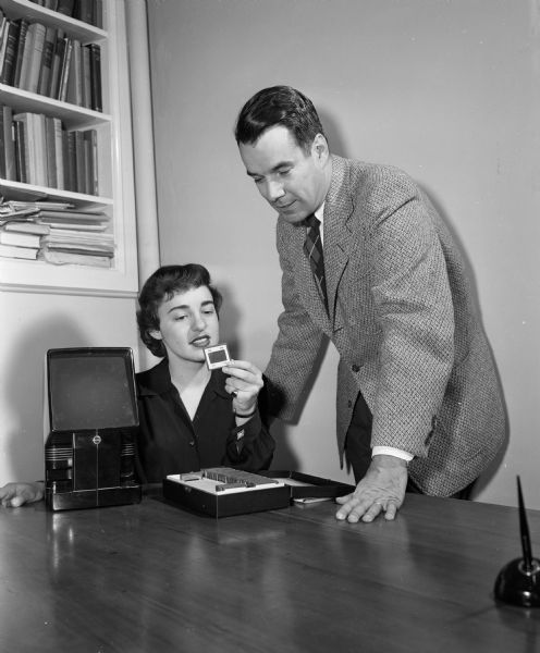 Dr. John V. Irwin (right), director of the University of Wisconsin's speech and hearing clinic and professor of speech, oversees graduate student Elinor Miller as she examines a slide. Miller's master's degree thesis was on "Articulation of Testing in the Diagnosis of Speech Problems in Children with Cerebral Palsy."