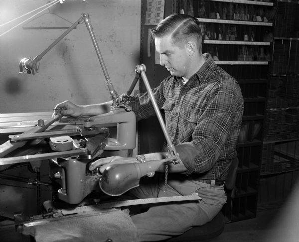 Portrait of Eldon Vondra at his job as as engraver at the Varigraph Company, makers of mechanical lettering instruments. Five of the 10 Varigraph employees are persons with disabilities, including owner Frances Chamberlin. Mr. Vondra is part of the 'Madison Story' — the account of the opportunities this city offers its handicapped men and women who want a chance to work and enjoy the lives of self-supporting citizens.