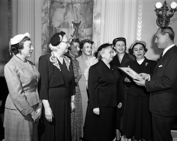 Governor Walter Kohler is presented with flowers from a group of Wisconsin Hadassah women during the World Jewish Child's Day commemoration. Pictured with Governor Kohler are (left to right): Rose Juranek, Pauline Sinaiko, Elizabeth Woods, Pauline Temkin, Fanny Mack, Anne Wolman, and Leah Brazy.