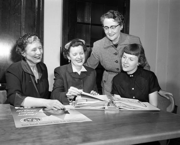 Three members of the Dane County Medical Society Women's Auxiliary show a Nursing Career Book to Carolyn Mitchell, who will be entering nursing school. The auxiliary assemble and distribute these books to high school guidance departments in order to promote nursing as a career. The auxiliary members are, left to right: Eylene Sherman, Agnes Hill and Lucille Fosmark.