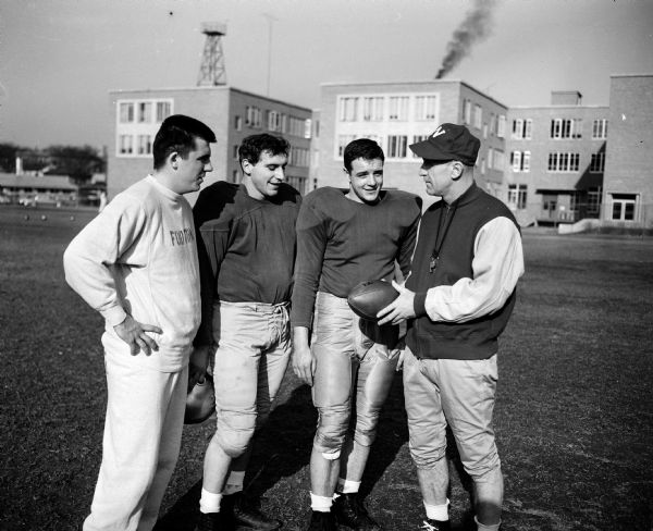 Ivan "Ivy" Williamson, Wisconsin's head football coach since 1949, talks with three of his veteran players during the Badgers' spring practice. Left to right are Jim Haluska, quarterback in 1952; Alan (The Horse) Ameche, All-American fullback, and Gary Messner, captain-elect of the football team.