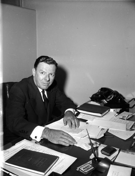 Portrait of Milwaukee Braves general manager John Quinn(?) seated at a desk.