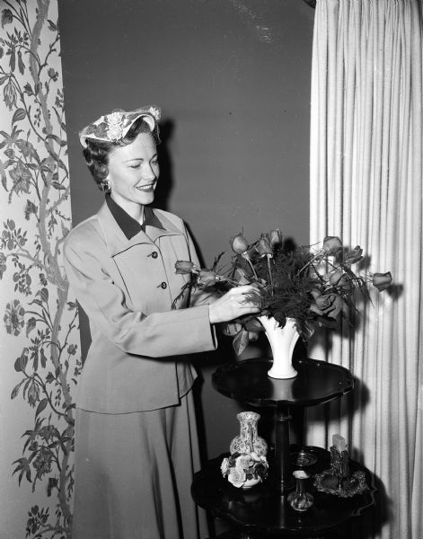 Elizabeth Vogts is making a flower arrangement while wearing an Easter hat made of imported toyo straw.