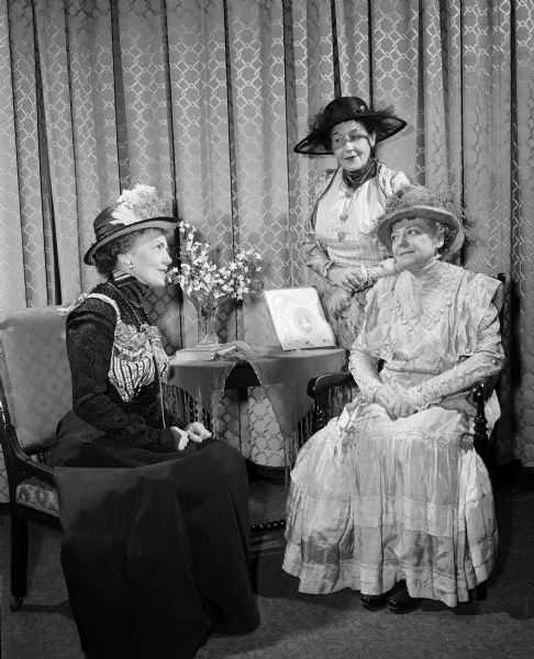 One of a series of scenes from a dramatic production: "Down Memory Lane," presented in celebration of the 60th anniversary of the founding of the Madison Woman's Club. Reenacting the founding of the club in 1893 in the home of Mary Atwood are, from left: Florence Jacques, playing the part of the club president, and club members Lorraine Rucker and Gladys Reynolds. The women are wearing period costume.