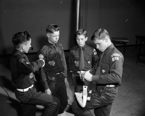 Scouts from Nichols School prepare the flag for the Explorer Court of Awards that preceded the Boy Scout Explorer Ball held at the Army Reserve armory. They are Fred Schulze (left), Edwin Bible, and Donald and Ronald Brown.