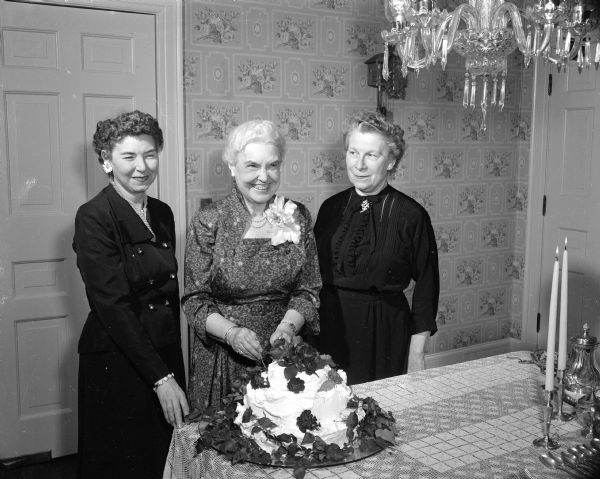 Irene Eastman, assistant professor in the UW music department, stands with a cake as she is being honored by alumnae and active members of Sigma Alpha Iota, a national professional music fraternity. At left is Winifred Brown and at right, Josephine Iltis.