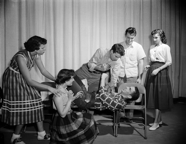 The actor at center menaces a reclining actor with his fist as four others look on. Shown left to right, on stage, are: Clara Vick, Pat Kelley, George Schaefer, John Cnare, Hiram O'Kane, and Fay Taffet.