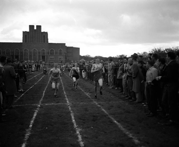 Participants cross the finish line of the 880-yard run at the city track meet held at Madison East High School athletic field. Larry Graham of West, right, noses out Terry Hesse of East, left, and Dan Schumann of Central came in third.