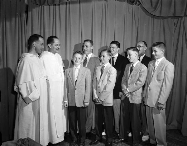 Blessed Sacrament Grade School athletes are honored at a banquet. Left to right: Pete Regsdorf, baseball captain; Jeff Cantwell, representing all the athletes; Jim Statz, football captain and Pat Lyons, basketball captain. At left are two Blessed Sacrament priests, left to right: Revs. Paul Fruendoff and Thomas Cain.  Standing behind the students are Jim Clapp, school football and basketball coach; his assistant, Mike Donagan and Ray Sweeney, baseball coach.
