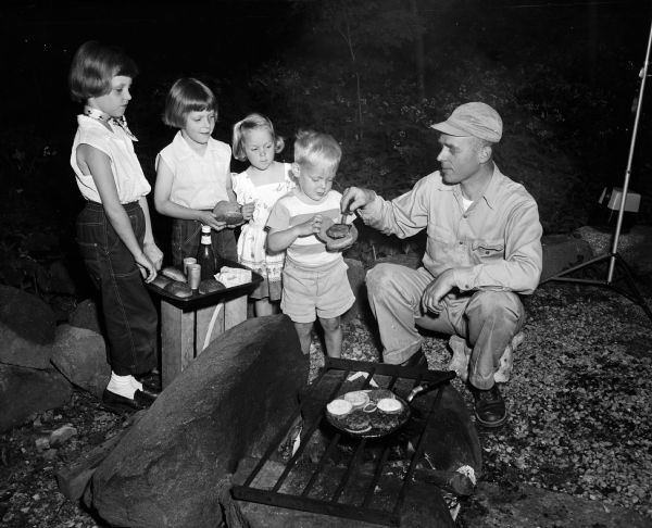 K.P. Buchholtz serves his four children hamburgers cooked on an outdoor grill. They are, from left, Kay, 9; Emily, 7; Paula, 4; and Louis, 3.
