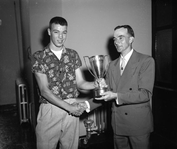 Harrison (Sandy) Smith, left, receives the Boy's Why Club Trophy from Coach Hal Metzen at Wisconsin High School's annual awards program. Smith was an outstanding basketball player.