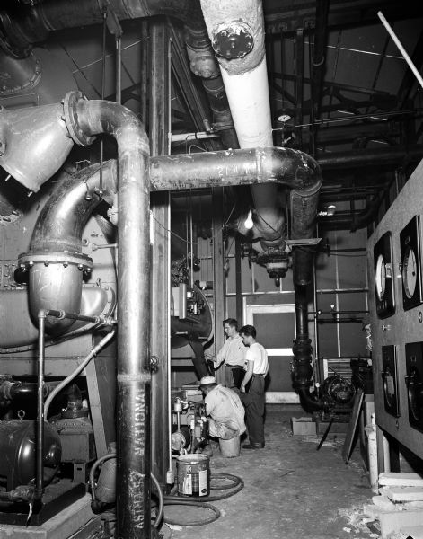 Three men examine pipes inside the Oscar Mayer plant.