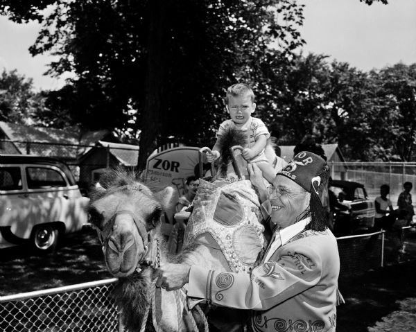 Zor Shrine member Henry R. Schroeder giving a boy a camel ride at Madison's Vilas Park Zoo.