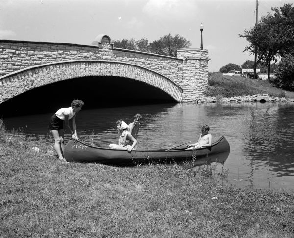 The East Washington Avenue bridge was chosen as the point where a simulated atom bomb struck Madison during a civil defense test, unbeknownst to four canoeists tending their boat at the shore by the East Washington Avenue bridge. Shown left to right are the "victims," Sharon Syse, Jane Nedderman, and Robert and Gerry Rogers.