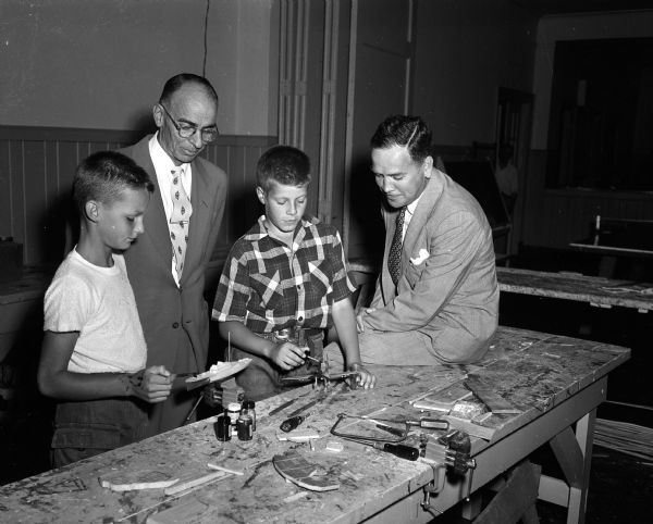 Tim Robbins and John Christensen show their craft projects at the YMCA to Robert W. Anthony (right), the associate chairman of the 1954 United Givers Campaign which supports the YMCA. Looking on is Loren Cockrell, secretary of the YMCA.