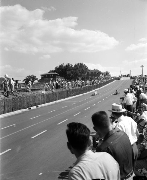 The crowd watches as two racers come down the Midvale Boulevard hill during the 1954 Madison soap box derby.