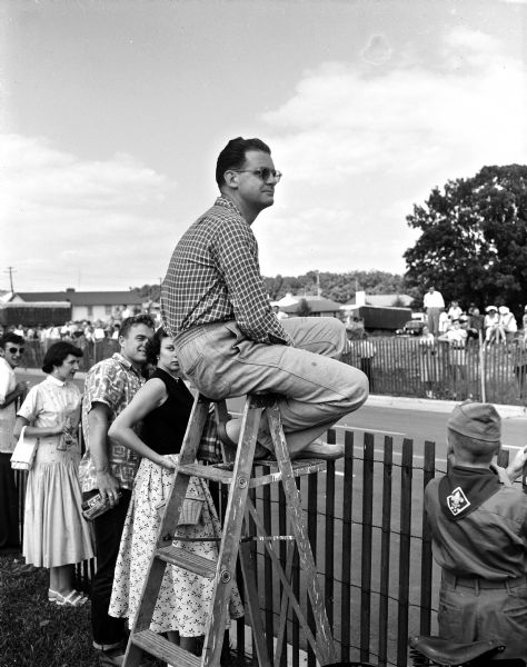 Guy Beaumont of Madison sits atop a ladder to watch the races at the 1954 Madison soap box derby.