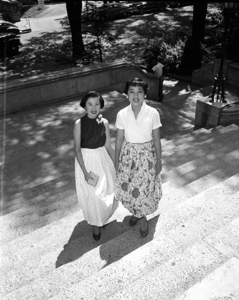 International Students attend summer school at the University of Wisconsin. Pictured are Sylvia and Leonor Hernandez, sisters from Manilla, Philippines, who came to Madison on September 1953 and will return to Manilla in June 1955. Sylvia is studying for her master's degree in agricultural journalism and Leonor is doing graduate work in speech. They are on the east steps outside the Memorial Union.
