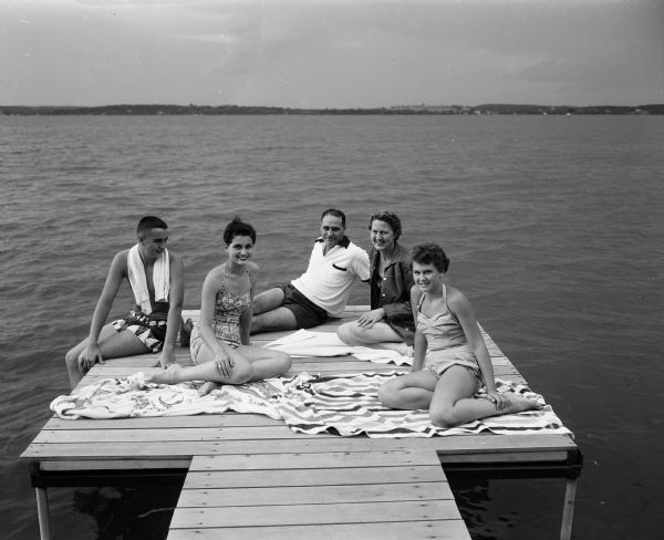 Dr. Anthony and Mrs. (Dorothy) Curreri of 3636 Lake Mendota Drive relax on their pier with children Bill, Cynthia, and Bonnie. They all enjoy swimming in Lake Mendota behind their home.
