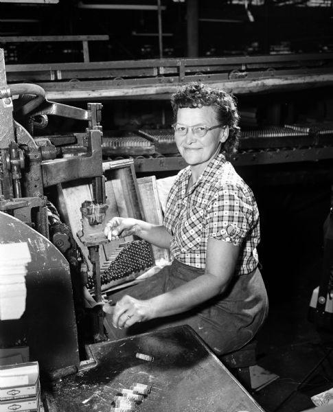 Clara L. Anderson of McFarland operates a machine that puts labels on small batteries. She works at Ray-O-Vac and is a leader in Local 19587, Battery Workers' union of the American Federation of Labor.
