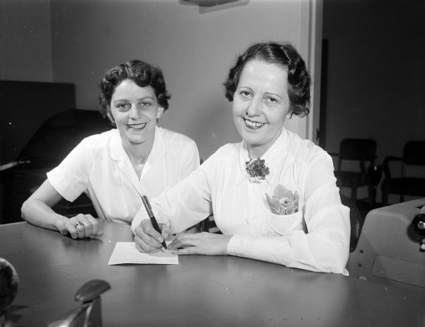 Ruby Allman (right), secretary of Local 538 Amalgamated Meat Cutter and Butcher Workmen of North America at Oscar Mayer and Company, signs up Dorothy Braund, a new employee.  In the middle of the Gread Depression, Oscar Mayer recognized AMCBW to represent their workers.