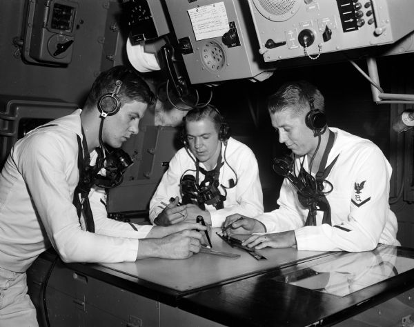 Naval reservists Don Lunde, Don Borland, and Richard Olson, left to right, all radarmen, man a combat information center at the Naval Reserve Training Center at 1046 East Washington Avenue in Madison.