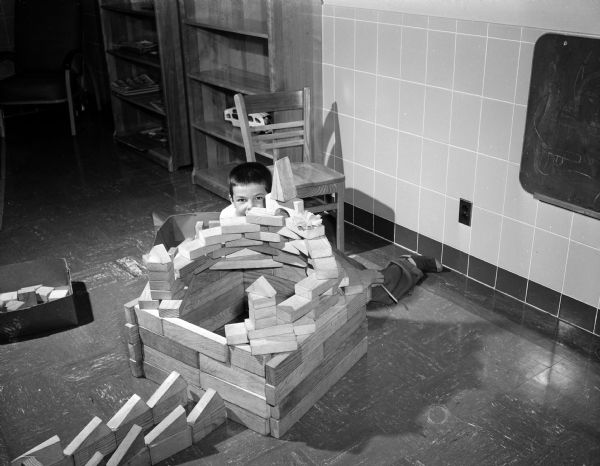 A young boy plays with building blocks at the Wisconsin Diagnostic Center for the intensive study of mentally and emotionally disturbed young people. The boy was referred by the state Department of Public Welfare; the center is under the supervision of the Mental Hygiene Division of the State Department of Public Welfare and connected with the University of Wisconsin Medical School as a training ground for medical students and future psychiatrists. The center is located at 1552 University Avenue.