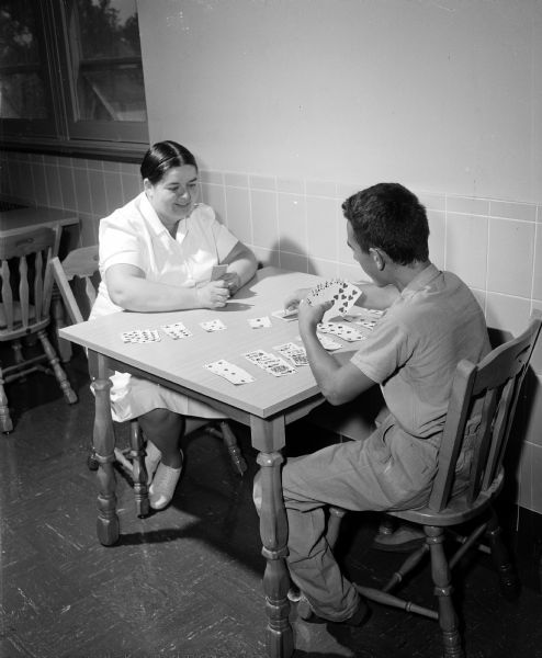 A patient plays cards with Eugenia Hoover, a psychiatric aide, at the Wisconsin Diagnostic Center at 1552 University Avenue. The Center is for the intensive study of mentally and emotionally disturbed young people, referred to it by the state Department of Public Welfare. It is under the supervision of the Mental Hygiene Division of the State Department of Public Welfare and connected with the University of Wisconsin medical school as a training ground for medical students and future psychiatrists.