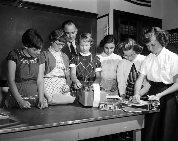 Students at Sunnyside School, 3902 East Washington Avenue, count money from the school lunch program with guidance from school principal George Dohms. Left to right are Mary Ellen Beaker, Betty Heinigen, Elma Kristol, Mira Armstrong, Jean Fleury, and Mary Ellen Lehr.