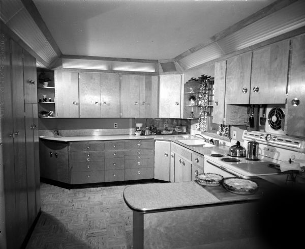 Interior view of the kitchen of the Ernie Terhill house in Sun Prairie at 560 Kelly Street.  The kitchen contains cabinets, an electric stove, and a work surface holding two pies.