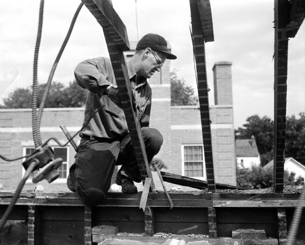 A member of Bashford Methodist Church, 15 North Seventh Street, tears down the house at 329 North Street where the new church will be located. Searl Cook is shown sawing on a beam.