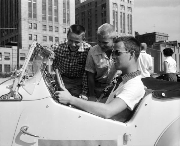 Three young men try an MG for size at the Madison Sports Car club "rallye." They include, from left: Tom Wengel, Dennis Gunderson, and Donn Gurney.