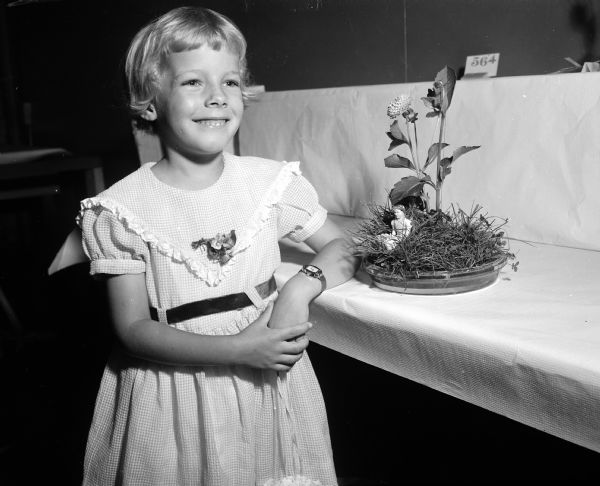 Mary Louise Peterson, age 6, posing with her flower arrangement exhibit called "Miss Moffet" at the annual Badger State Dahlia Society flower show.