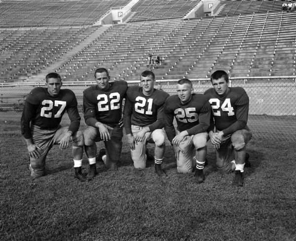 Group portrait of five quarterbacks, including Dick Frecka, #27; Glen Wilson, #22; Jim Miller, #21; Dick Simonson, #25; and Jim Haluska, #24.