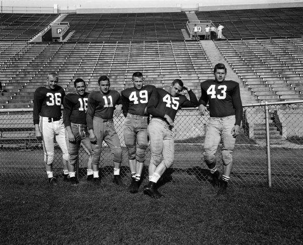 Group portrait of six candidates for right halfback, including John Weinert, #36; Bob 'Tuffy' Young, #16; Dave Strehlow, #11; Billy Lowe, #49; Clarence Bratt, #45; and Dick Kolian, #43.