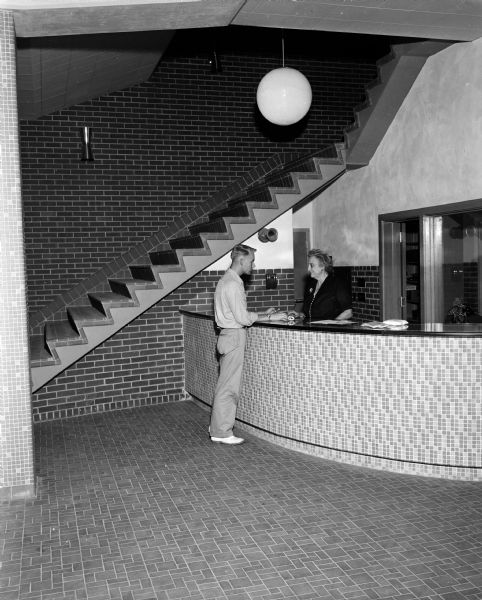Paul Worthington receives his mail from Emma Dais, chief clerk and housemother, at the reception desk at the newly built University of YMCA at 306 North Brooks Street.