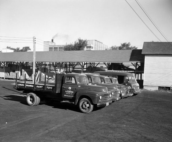 View of C.C. Collins & Son, Inc. trucks, parked at 2308 University Avenue. "Lumber, Woodwork, Paint, Toys" is painted on side.