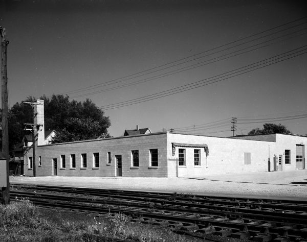 Exterior view of the Milwaukee Cheese Company building at 1133 East Wilson Street.  The company was founded by the Zwicky Brothers in 1912 and they opened a branch in Madison in 1932 at 301 South Few Street. They moved to East Wilson Street on September 15, 1954. Railroad tracks are in the foreground.