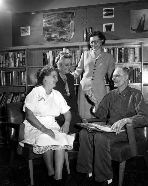 Three members of the Madison Business and Professional Women's club employed at the Veterans' Administration hospital are chatting with Gustave Johnson of King, Wisconsin, a patient at the hospital. The women are Evalyn Henriot, voucher auditor in the finance division of the hospital; Agnes Hemingway, a nurse's aid in the rehabilitation ward, and Nellie A. Lynch, a nurse's aid for Ward 4-A at the hospital.