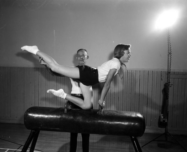 Gymnastic instructor Edward Strobel spots student Virginia Hollfelder as she practices on the side horse for the Madison Turners 1955 Centennial Celebration.