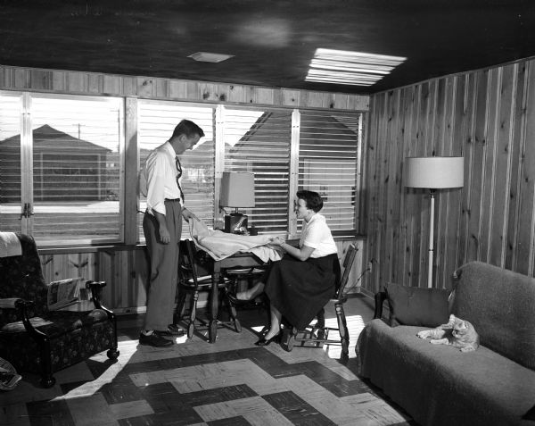 Portrait of Charles and Elaine Berigan in the new breezeway at their home at 26 Walter Street. A cat is sitting on the couch on the right.