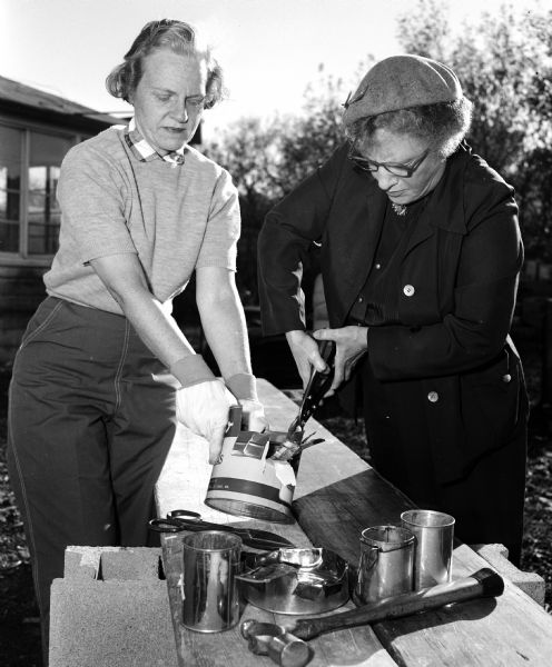 Helen Giessel (left) and Avis MacLean make an improvised plate and cup during a Civil Defence emergency mass-feeding practice event.