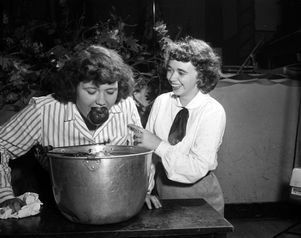Carol Hanson bobbing for an apple as Donna Tupper laughingly looks on.