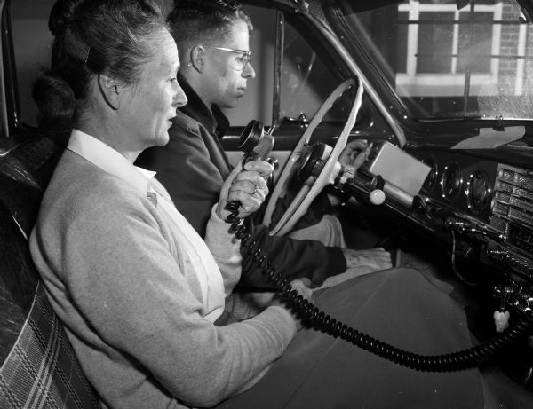 Ida Huff and William Aspinwall, Jr. answer a surprise alert phone call for a test of emergency services response while seated in an automobile.