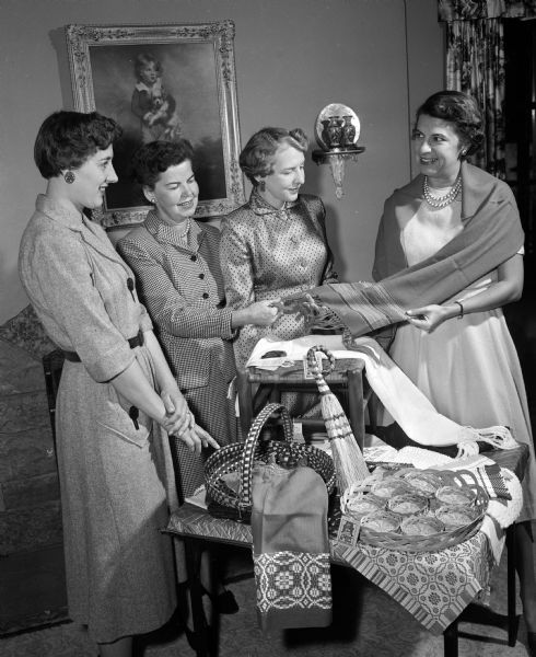 Four alumnae of the Madison Pi Beta Phi sorority looking at a collection of Arrowcraft products handmade by a Settlement school at Gatlinburg, TN. The items will be sold at an upcoming Phi Beta Phi tea. The women include, from left:  Mary Stark, Marion Stevens, Janet Woodman, and Barbara Shaw.