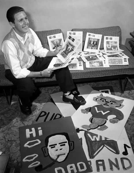 University of Wisconsin law student Joseph L. Stone, of Chicago, in charge of the card block cheering section for football games, is shown with diagrams of creations his committee made for the homecoming game against Northwestern University.