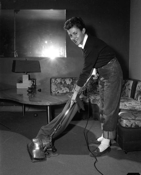 Stewardess Ruth Otto cleaning an apartment at 3160 East Washington Avenue which she shares with two other stewardesses. The photograph was taken to accompany an article about the daily lives of six North Central airline stewardesses assigned to Madison as their home base.