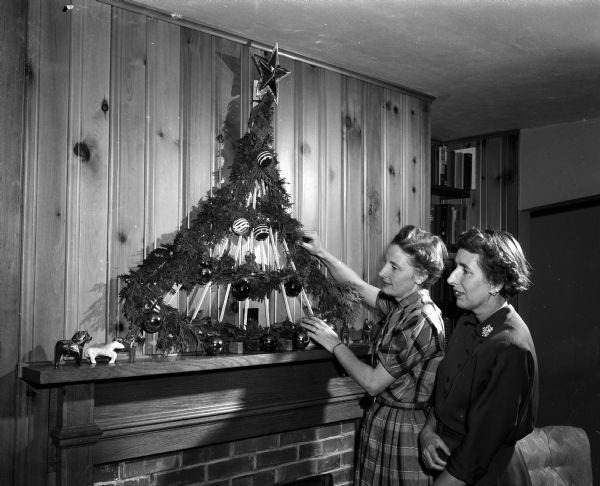 Mrs. Elwin Willett of 4115 Jerome Street (left) and Mrs. Robert (Helen) Brettell of 4603 Gordon Avenue, president of the Ladies Fellowship at Lake Edge Congregational Church, 4200 Buckeye Road, admire a wooden trellis decorated for the holidays. It is one of the items displayed for sale at the church bazaar.