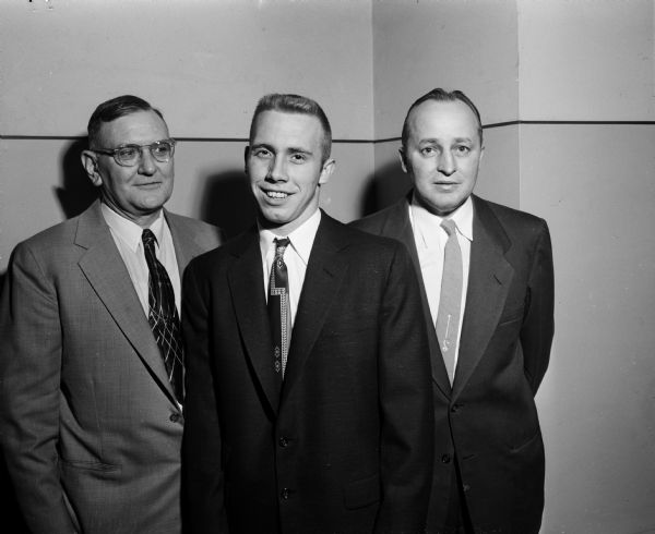 Portrait of Principal A.J. Barrett, football captain Dick Barton, and football coach Herbert Mueller (left to right) at the Madison East High School football banquet. Dick Barton was selected on the all-city and Big-Eight teams and voted most valuable player in the Big-Eight conference.