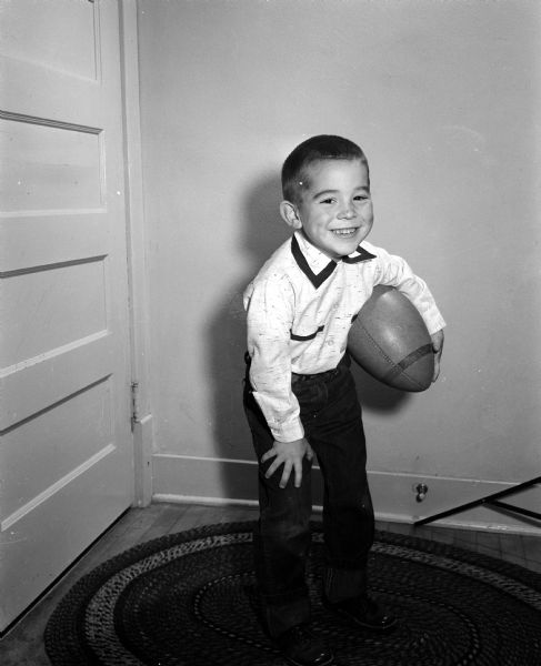Jeffery Radder, age five, holds a football he received from the Empty Stocking Fund, as imagined in Monte Allen's dream. The Club, sponsored by the <i>Wisconsin State Journal</I>, raises funds for Christmas toys for needy children in the Madison area.